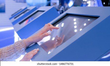 Education And Technology Concept - Woman Using Interactive Touchscreen Display Of Electronic Kiosk At Technology Exhibition