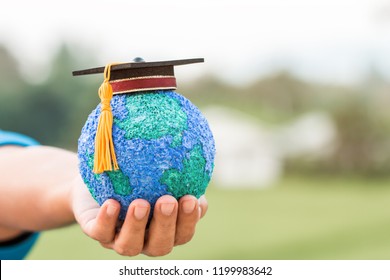 Education World Knowledge Ideas. Graduation Cap On Businessman Holding Paper Mache Craft Earth Globe In Hands. Concept Of Global Business Study Abroad Educational On Green Blackground, Back To School