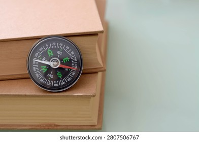 Educational Direction Concept with Compass on Stack of Old Books