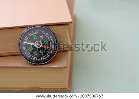 Educational Direction Concept with Compass on Stack of Old Books