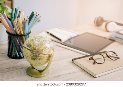 Educational e-learning concept with a globe, tablet, headphones, glasses, notebooks, pencils, pens, in various colors, and books on a modern table. Set against a bright-toned leather shelf background - Powered by Shutterstock