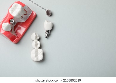 Educational model of gum with post between teeth, dental implant and mirror on grey background, flat lay. Space for text