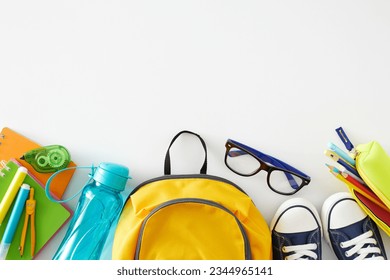 Educational process idea. Top view shot of pair of shoes, educational supplies, eyewear, water bottle, schoolbag on white background with empty space for promo or text