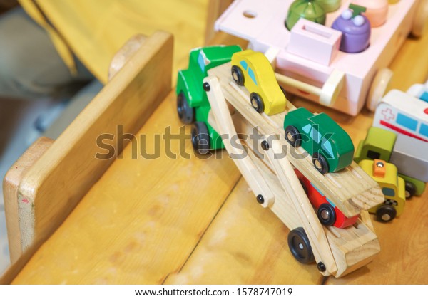 Educational toys for little kids. Train on the\
wooden table, with white wooden in the background. Baby. Fun. Happy\
Childhood. Close-up of a wooden toy truck\
