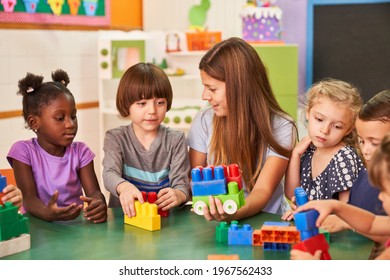 The educator and children in the international kindergarten play together with colorful building blocks - Shutterstock ID 1967562433