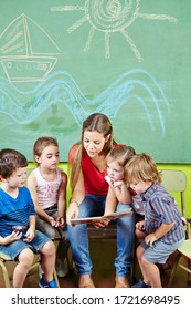 Educators And Many Children In A Group Read A Book In Kindergarten