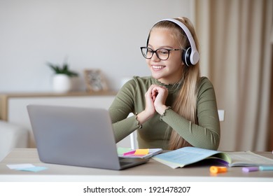 E-education, Online Lessons And Courses For Schoolers. Joyful Teen Blonde Girl In Headset Looking At Laptop Screen, Watching Online Lesson Or Listening To Tutor, Home Interior, Copy Space