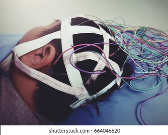 EEG Electrode Placement To Patient During EEG Record Of Beautiful Boy At Clinic. With Cross Processing Process.Film Grain,Noise