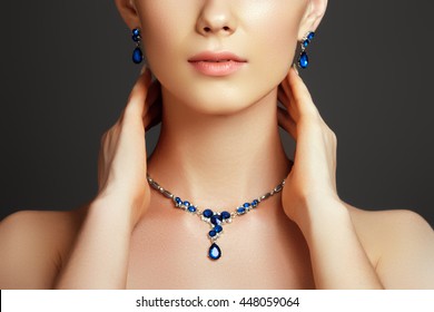 Eegant fashionable woman with jewelry. Beautiful woman with a sapphire necklace. Beauty young model with a diamond pendant on a gray background. Jewellery and accessories