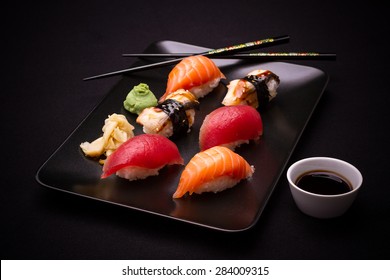 Eel, salmon and tuna sushi with chopsticks, dark background