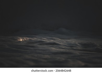 An Eerie Scenery Of The Sand Of The Ocean In Dim Lights At Night