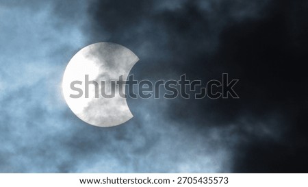 Eerie solar eclipse partially hidden by dark ominous clouds. A stunning celestial event evoking a sense of mystery, wonder, and astronomical significance.