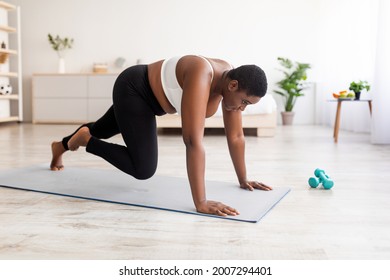Effective bodyweight exercises. Curvy black woman making strength workout, running with her hands on floor at home. Plus size young lady training her body, leading active lifestyle