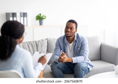 Effective psychotherapy. Young black guy talking to his psychologist, receiving professional help at mental health clinic. African American male patient sharing therapy results with counselor - Shutterstock ID 2067560870
