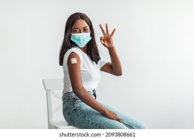 Effective Vaccine. Portrait Of Happy Smiling Black Female Patient In Face Mask Showing Vaccinated Arm With Sticking Patch On Shoulder After Getting Shot Against Flu Or Covid And Okay Gesture At Studio