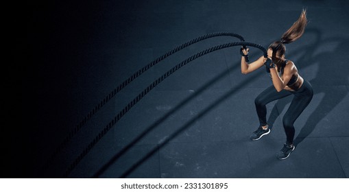 Effective Workout with a rope. Sportswoman trains in the functional training gym, performing crossfit exercises with a battle rope. - Powered by Shutterstock