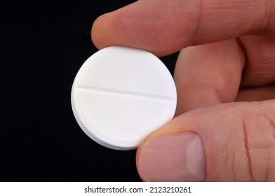 Effervescent aspirin pill held in hand close up on black background 