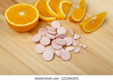 Effervescent Orange Tablets. Fizzy Fruit Tablets Pile, Disease Prevention Concept, Pink Orange Effervescent Vitamine Supplement On Wood Background