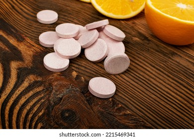 Effervescent Orange Tablets. Fizzy Fruit Tablets Pile, Disease Prevention Concept, Pink Orange Effervescent Vitamine Supplement On Wood Background