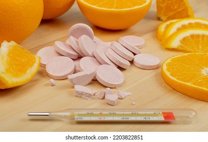 Effervescent Orange Tablets With Medical Thermometer. Fizzy Fruit Tablets Pile, Disease Prevention Concept, Pink Orange Effervescent Vitamine Supplement On Wood Background