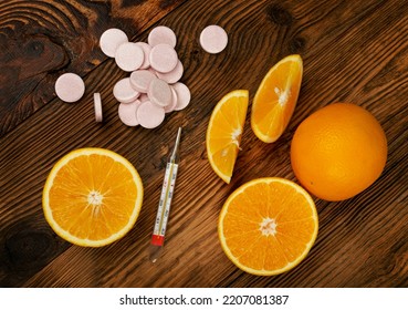 Effervescent Orange Tablets With Medical Thermometer. Fizzy Fruit Tablets Pile, Disease Prevention Concept, Pink Orange Effervescent Vitamine Supplement On Wood Background