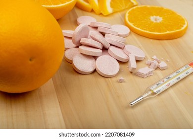 Effervescent Orange Tablets With Medical Thermometer. Fizzy Fruit Tablets Pile, Disease Prevention Concept, Pink Orange Effervescent Vitamine Supplement On Wood Background