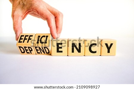 Efficiency or dependency symbol. Businessman turns cubes, changes the word dependency to efficiency. Beautiful white table, white background, copy space. Business, efficiency or dependency concept.