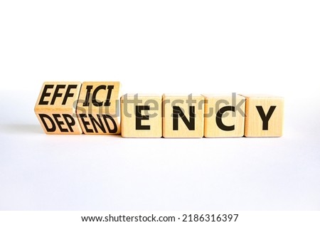 Efficiency or dependency symbol. Turned wooden cubes and changed the word dependency to efficiency. Beautiful white table, white background, copy space. Business, efficiency or dependency concept.