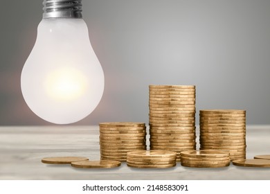 Efficiency and energy saving concept. Light bulb on, with Golden coins and energy bill. Increase in energy and gas tariffs.