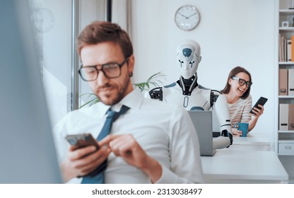 Efficient AI robot working in the office and lazy inefficient employees chatting with their smartphones - Powered by Shutterstock