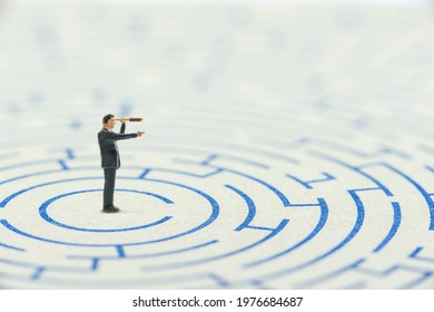 Efficient and effective way for a leader to solve or overcome problems and find solutions, business concept : Miniature CEO leader looks through a monocular in one direction to find the way to escape - Shutterstock ID 1976684687