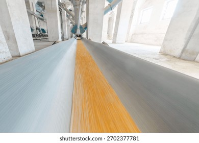 Efficient grain distribution with under-silo conveyor system transporting wheat in a production facility