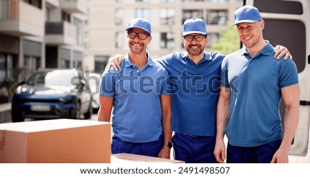 Efficient movers in uniform load and unload boxes from a van for a happy young homeowner with a professional moving company.