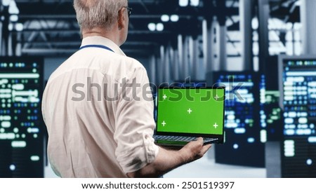 Efficient IT professional navigating network of server rigs in industrial hub. Expert using mockup laptop, ensuring proper operations, doing optimizations and maintenance in data center
