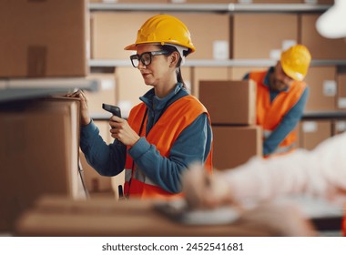 Efficient warehouse worker scanning a barcode on a delivery box label using a handheld scanner, logistics and shipping concept