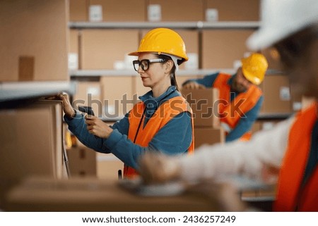 Efficient warehouse worker scanning a barcode on a delivery box label using a handheld scanner, logistics and shipping concept
