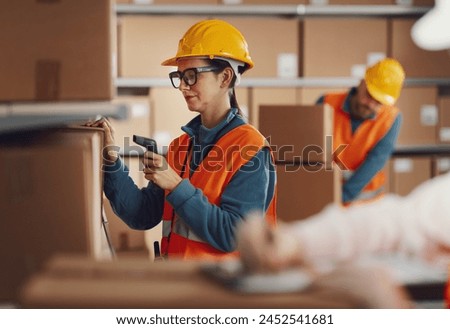 Efficient warehouse worker scanning a barcode on a delivery box label using a handheld scanner, logistics and shipping concept