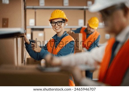Efficient warehouse worker scanning a barcode on a delivery box label using a handheld scanner, logistics and shipping concept