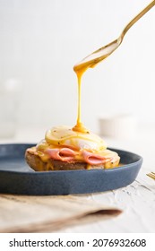 egg Benedict with hollandaise sauce on blue plate on table in white kitchen