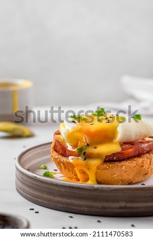 Egg benedict. Poached egg, ham, hollandaise sauce, onion on slice toast for tasty breakfast. vertical orientation. English brunch