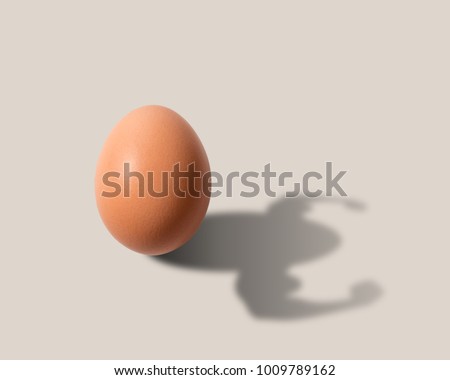 The egg casts a shadow in the form of a bodybuilder. Natural protein and vitamins. Food concept.