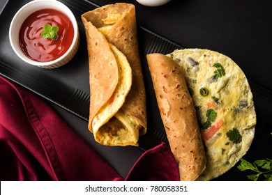 Egg Chapati - Omelette Roll or Franky. Indian Popular, quick and healthy recipe for kid's tiffin or lunch box. Served with tomato ketchup over moody background. Selective focus
