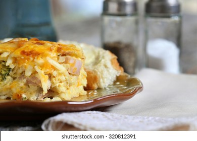 Egg, Cheese, Peppers, Onion And Sausage Breakfast Casserole Served With Coffee On 
A Rustic Table Plate, Fork And Napkin