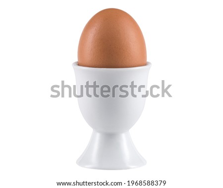 Egg in Egg cup. Ceramic eggcup for breakfast. Holder stand for boiled or raw chicken eggs on white isolated background. Macro close-up photography.