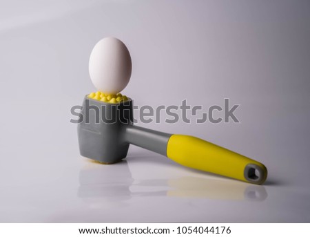 Egg and hammer on table. Symbol of strength, force and something hard and unbreakable. Concept of fragility and power, chicken