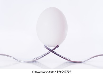 Egg Held Up On Two Forks. High Key Image.