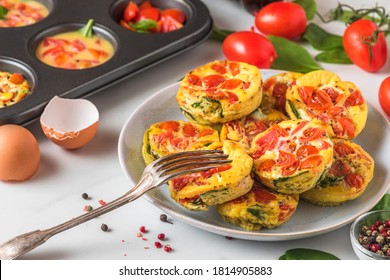 Egg Muffin Cups Or Omelette With Spinach And Tomatoes In A Plate And In Muffin Tin With Fork. Healthy Keto Diet Breakfast. Cooking Concept. Close Up