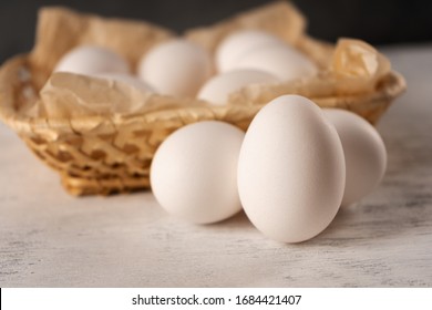 The Egg Near The Square Wicker Basket On A Light Wooden Surface.