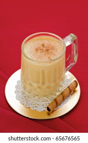 Egg Nog In Glass On Gold Coaster With Cookie On Red Background.