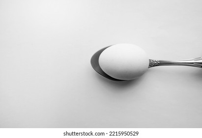 Egg On A Metal Spoon Top View, White Background, Space For Text